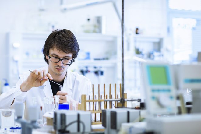 Young male researcher carrying out scientific research in a lab (shallow DOF; color toned image)